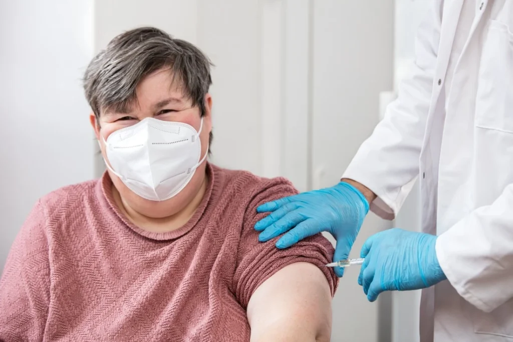 Disabled woman with down syndrome wearing mask while getting vaccination