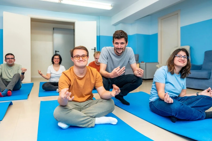 Group of disabled friends in yoga class with support worker